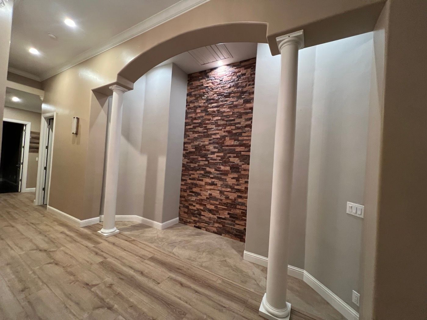 Hallway with an arch, columns and a stone accent wall after the job
