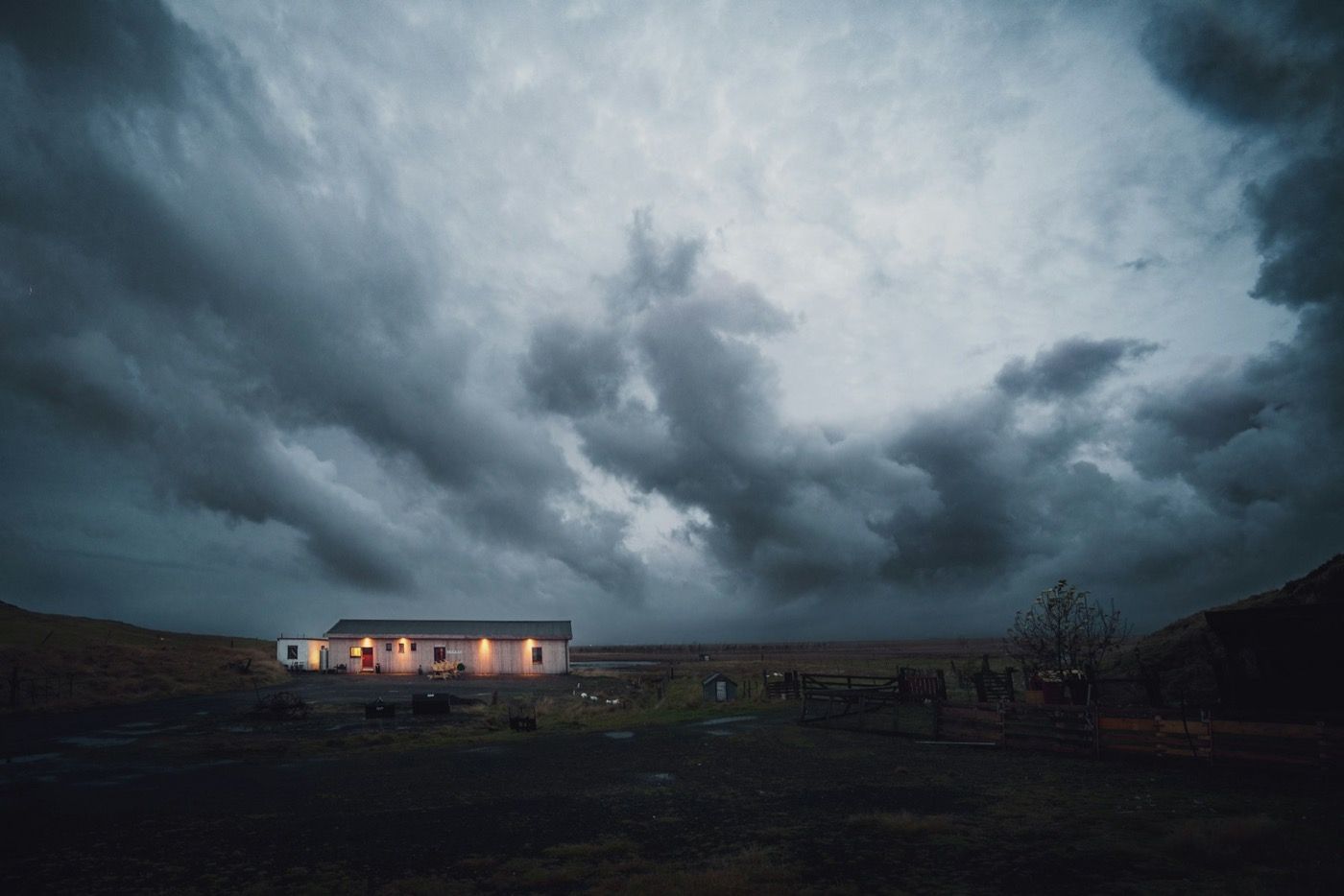Dark storm clouds over a house with its lights on