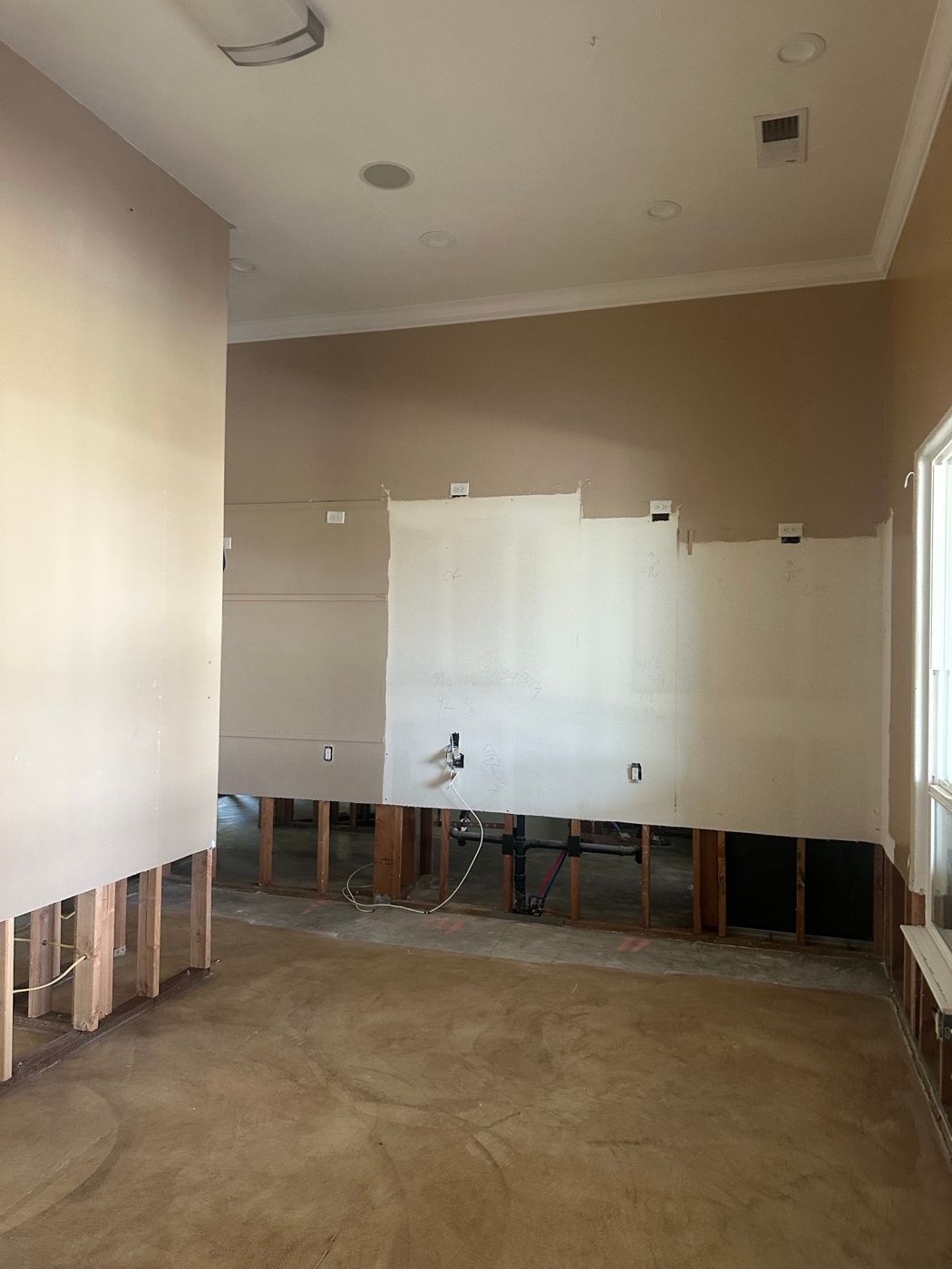 Living room with the lower drywall removed and framing exposed after water damage
